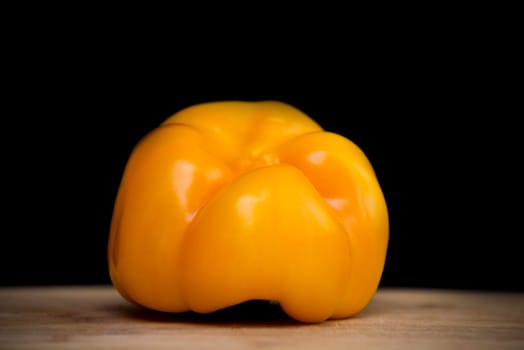 close up on yellow paprika on wood,black background