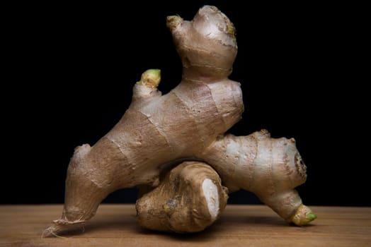 close up on fresh ginger on wood with black background
