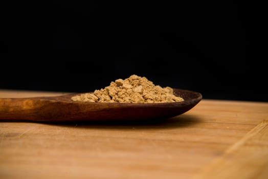 close up on powder ginger on wood with black background
