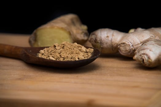 close up on fresh ginger and powder on wood with black background