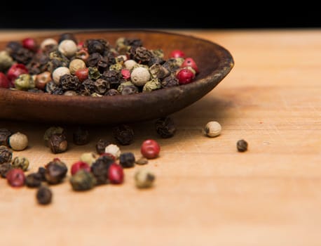 close up on pepper mix on wood with black background
