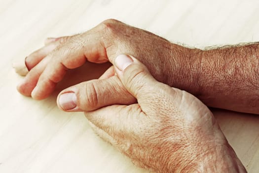 An elderly man has pain in his hands