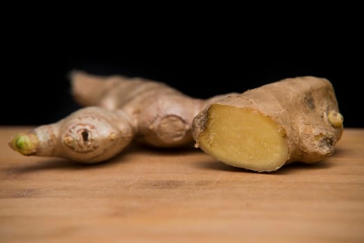 close up on fresh ginger on wood with black background