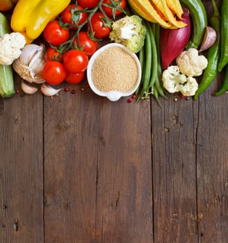 Raw Amaranth Grain in a bowl and vegetables on wood