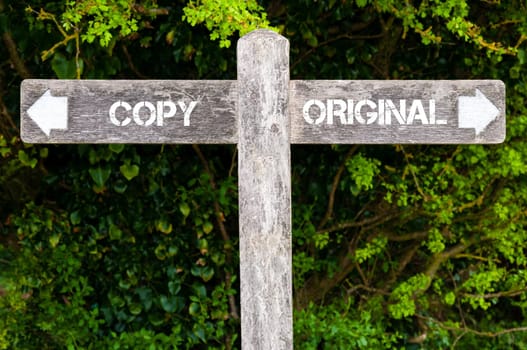 Wooden signpost with two opposite arrows over green leaves background. COPY versus ORIGINAL directional signs, Choice concept image