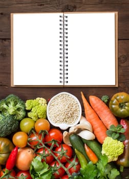 White sorghum grain in a bowl with vegetables and notebook on wood