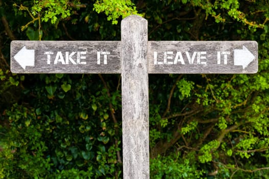 Wooden signpost with two opposite arrows over green leaves background. TAKE IT versus LEAVE IT directional signs, Choice concept image