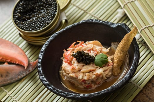 Crab meat in a dish on wood table with black caviar