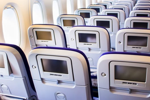 The interior of passenger airplane with the seats and screens