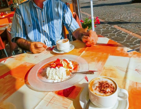 The dessert strawberries with cream and cup of coffe on the table of the outdoor cafe on the italian sidewalk. Taken during Italian vacation.