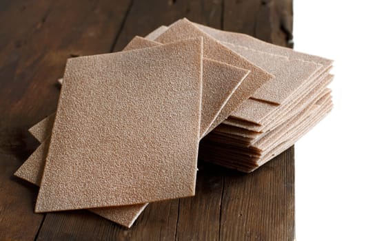 Raw lasagna sheets on a wooden table close up
