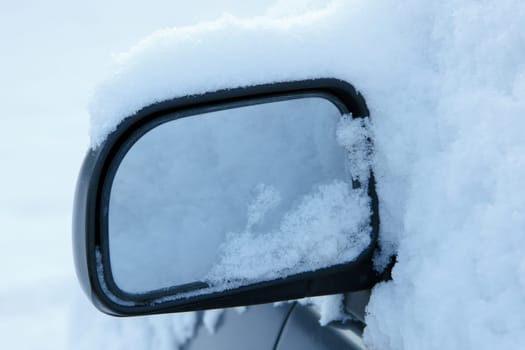 A car mirror covered in white snow