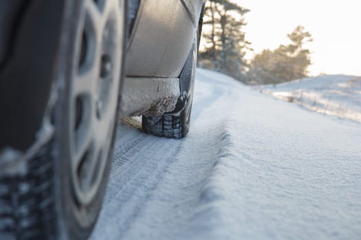 Car wheels leaving tracks on a snowy road