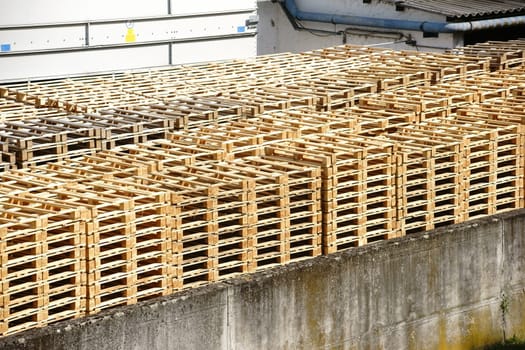 Stacked wooden pallets stand in the backyard of a factory.