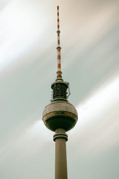The lower view of the Berlin TV Tower with blurred clouds in the background.