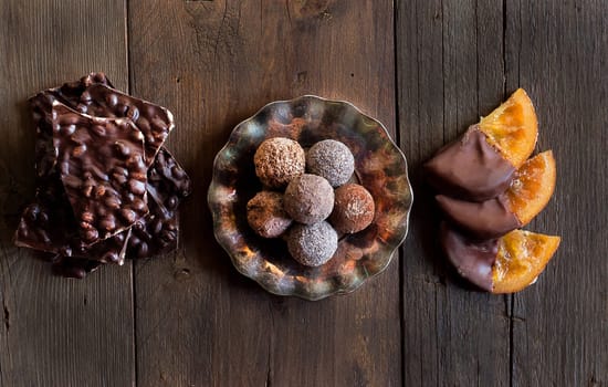 Chocolate, truffles and orange slices in dark chocolate on a wooden table