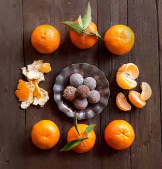 Chocolate truffles and tangerins on a wooden table