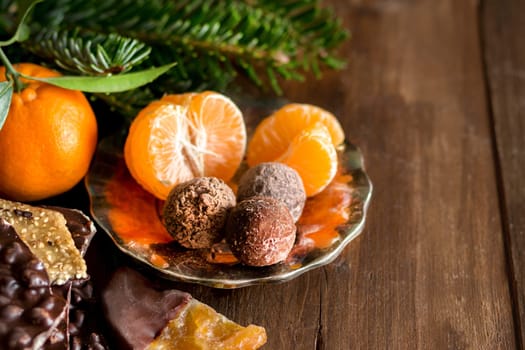 Chocolate, truffles and tangerins on a wooden table