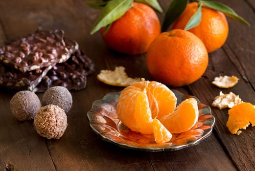 Chocolate, truffles and tangerins on a wooden table