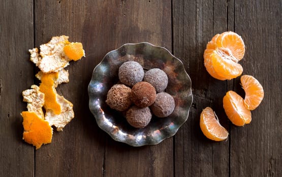 Chocolate truffles and tangerins on a wooden table