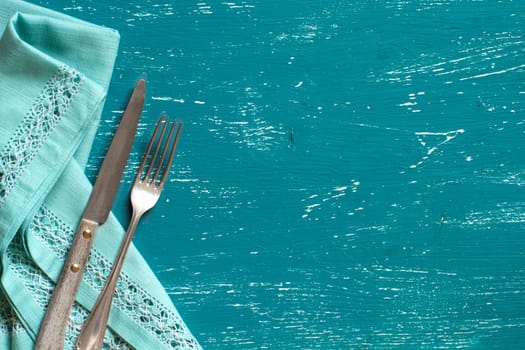 Vintage fork and knife on napkin on a turquoise wood