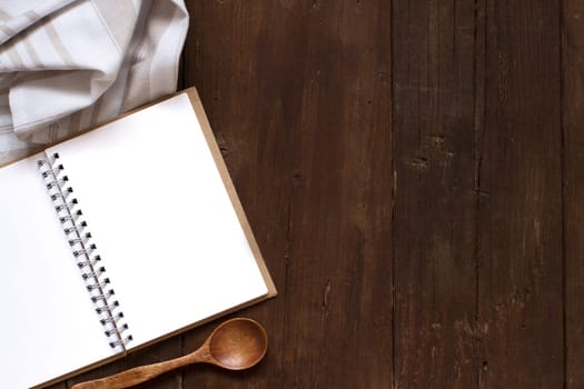 Blank cooking recipe book with spoon and napkin on a wooden table