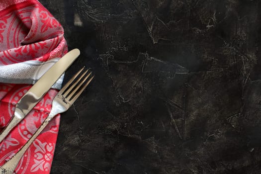 Vintage fork and knife on napkin on a dark background