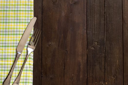 Vintage fork and knife on a colorful napkin on wooden table