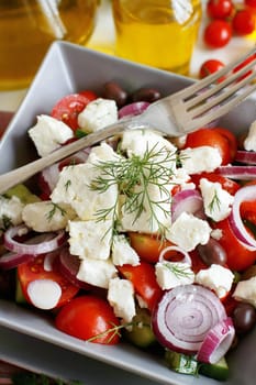 Greek salad with tomatoes, feta cheese, cucumbers, onions and olives