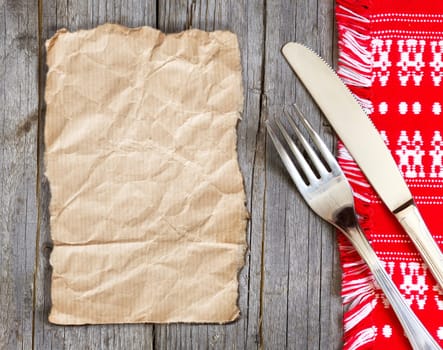 Fork and knife on kitchen towel and old wooden table