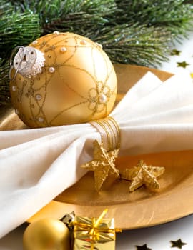 Festive table setting with golden bauble and plate