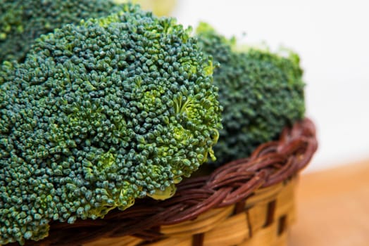 close up on fresh broccoli in basket solated on wood and white background