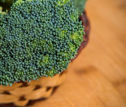 close up on fresh broccoli solated in basket on wooden background