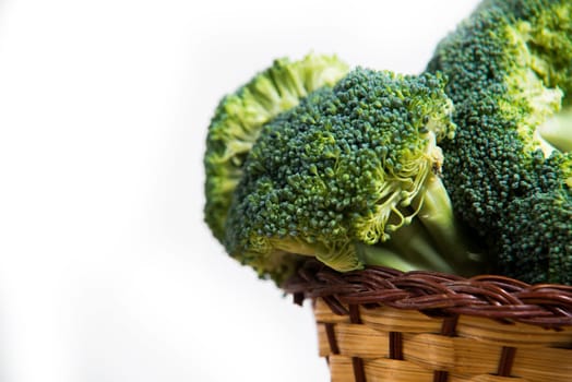close up on fresh broccoli solated in basket on wood and white background