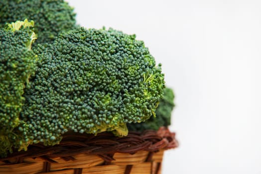 close up on fresh broccoli in basket solated on wood and white background