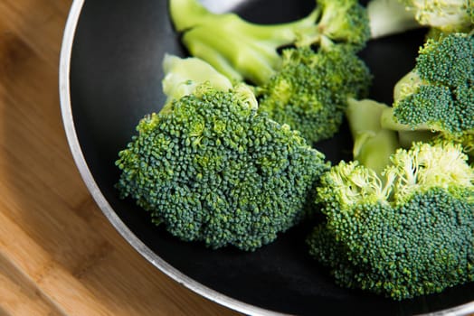 close up on fresh broccoli solated in pan on wooden background