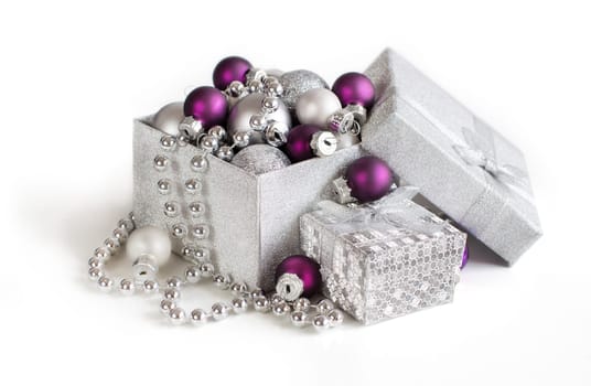 Silver and purple Christmas ornaments in gift box on white background