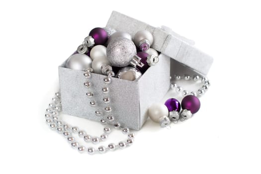 Silver and purple Christmas ornaments in gift box on white background