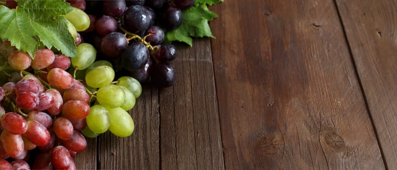 Grapes with leaves on a dark wooden table