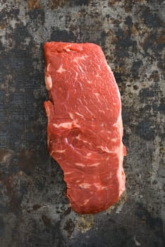 Uncooked rump steak on dark rustic background