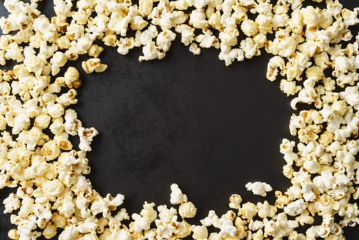 Frame of popcorn on dark textured background with copyspace