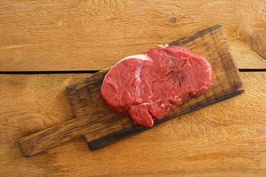 Uncooked fillet steak on wooden board on wood