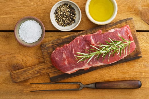 Uncooked rump steak on wooden board on wood