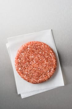 Burger patty from ground beef on parchment paper on stainless steel