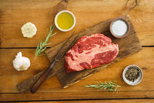 Uncooked chuck eye steak on wooden board on wood