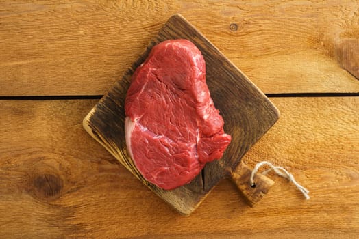 Uncooked fillet steak on wooden board on wood
