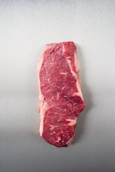 Uncooked rump steak on stainless steel from above