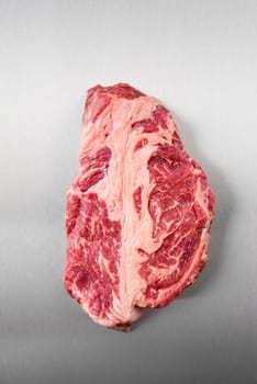 Raw chuck eye steak on stainless steel