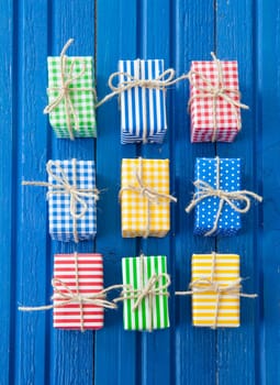 Small colorful gifts on a rustic background of blue wood