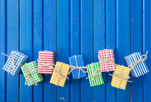Small colorful gifts on a rustic background of blue wood